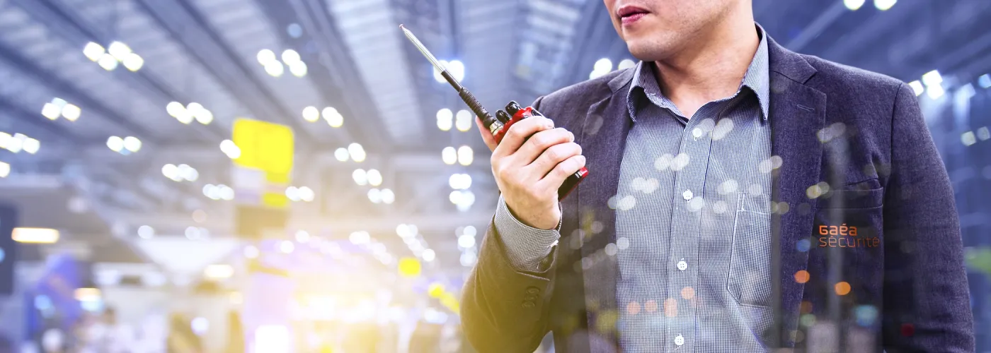 Un agent de sécurité GAEA Sécurité utilisant une radio de communication lors d’un événement, assurant la coordination et la surveillance en milieu sécurisé.