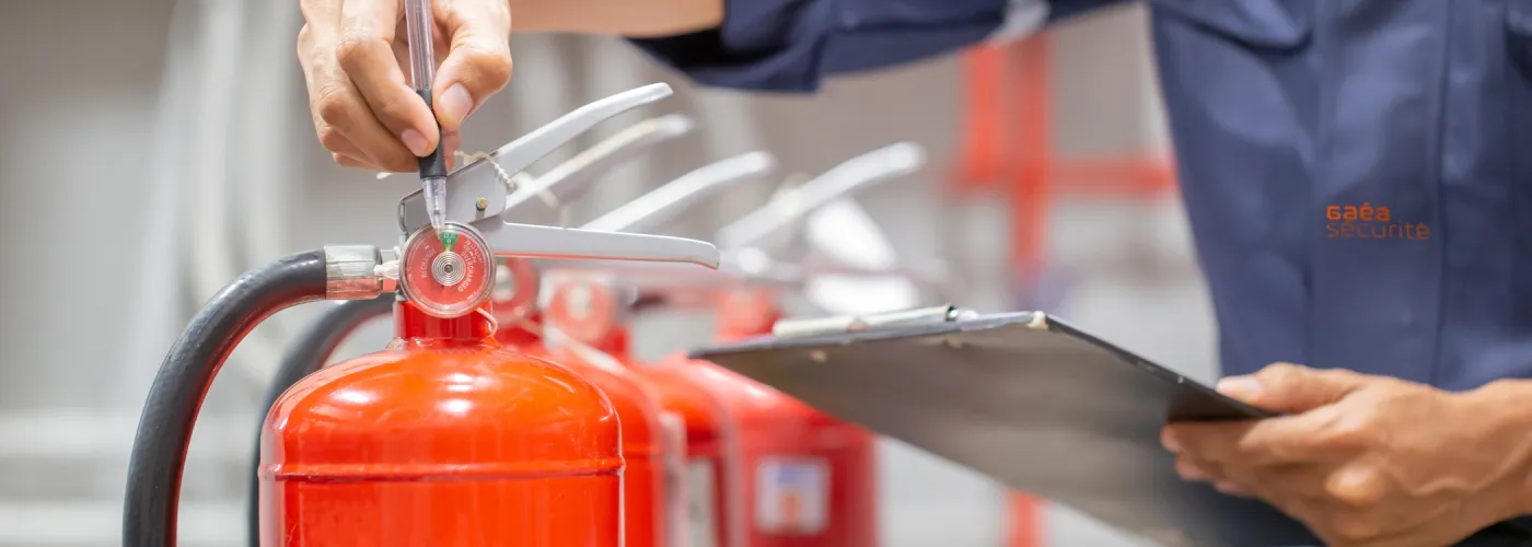 Un agent de sécurité incendie effectuant une vérification d’extincteur, garantissant la conformité et l’efficacité des équipements de lutte contre l’incendie.