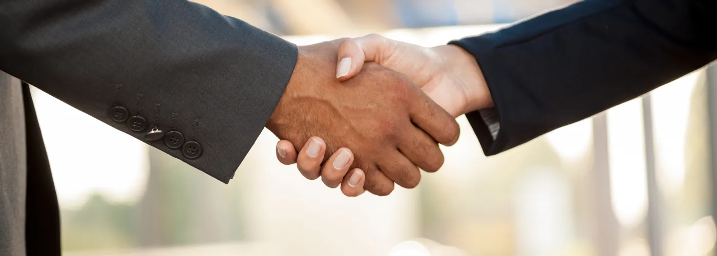 Poignée de main entre deux personnes en costume, symbolisant la confiance, le partenariat et l'engagement professionnel.